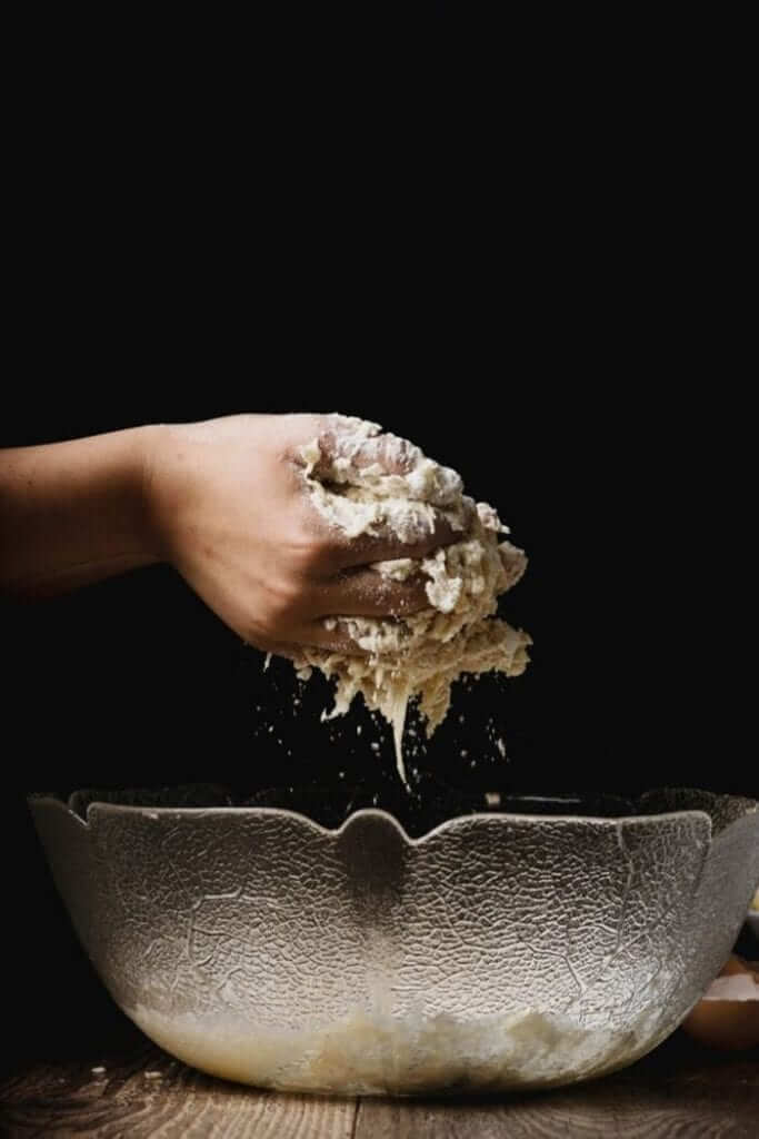 hands mixing healthy cookie dough in a glass bowl to make paleo snickerdoodle cookies 