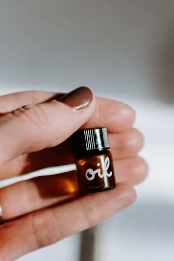 a woman's hand holding a small bottle with essential oil
