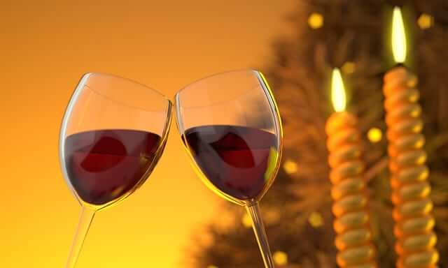 two glasses of red wine with Christmas lights in the background