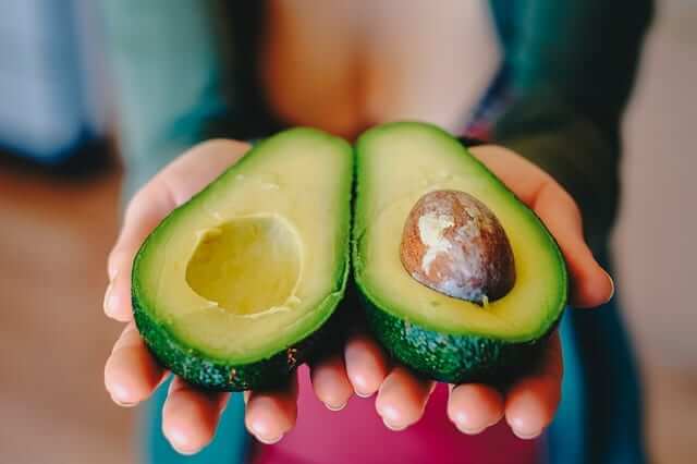 a woman holding a halved avocado