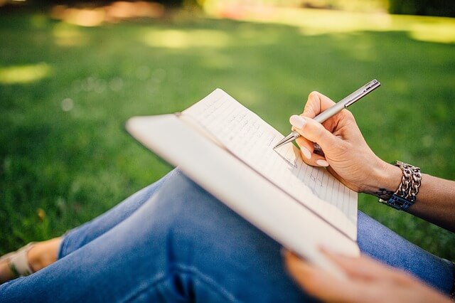 a woman under a tree writing a gratitude list