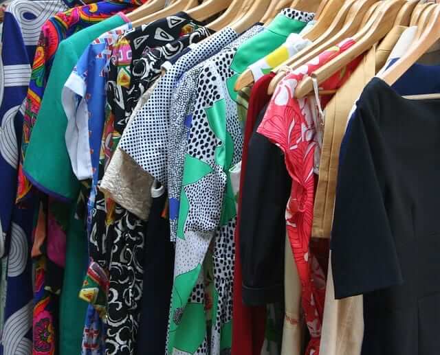 a closet full of clothes on wooden hangers