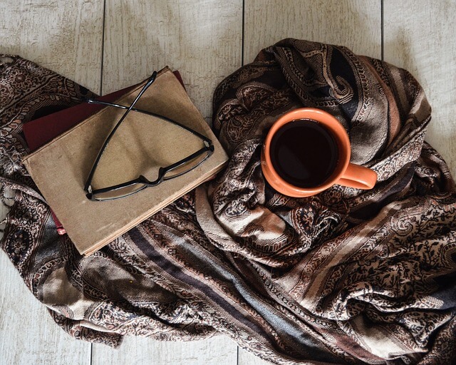 a cup of tea and a book with some glasses resting on top (self care-activities)