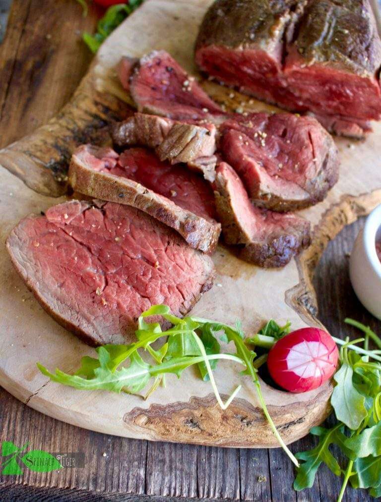 medium-rare Beef Tenderloin roast cut into slices on a wooden board