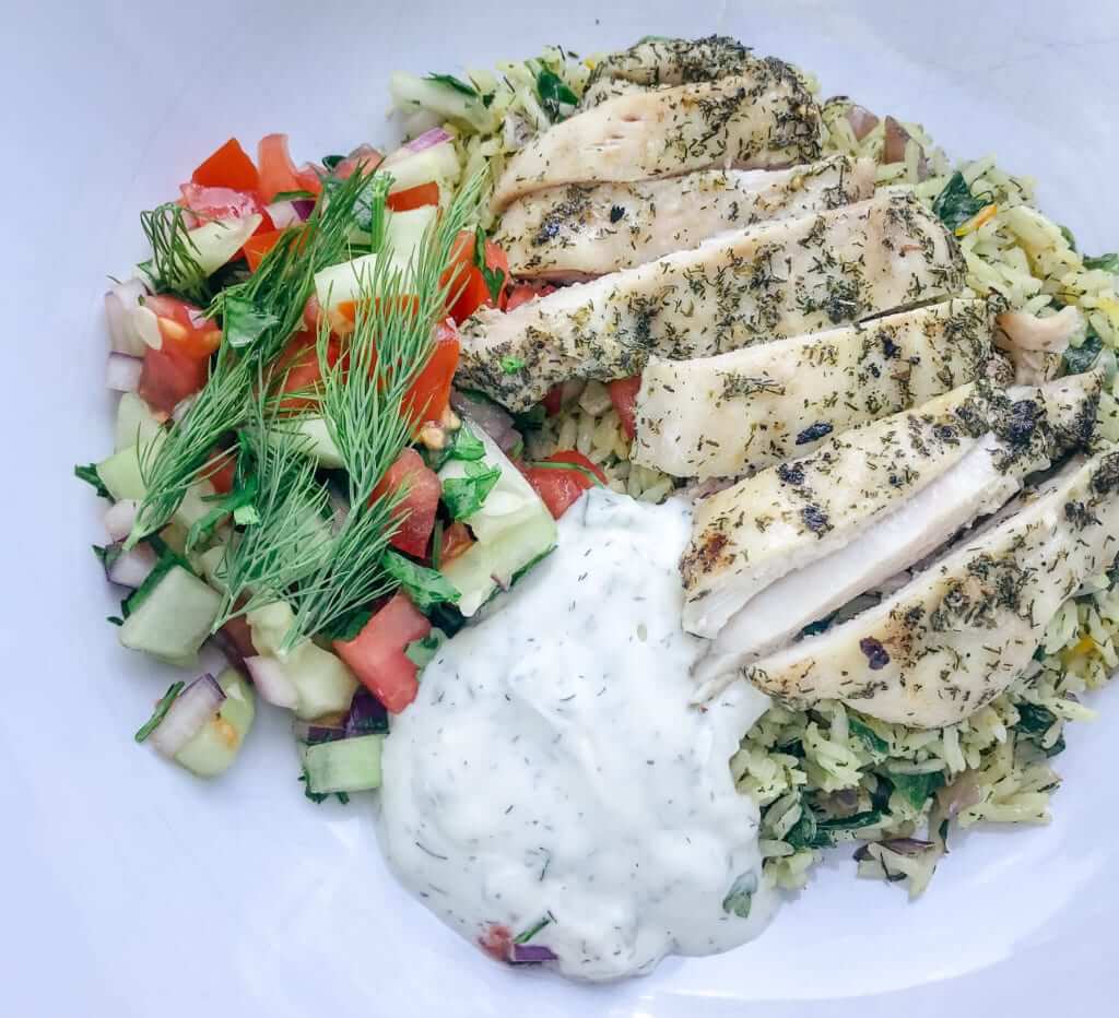 overhead shot of a healthy Greek marinated chicken and rice bowl with tzatziki 