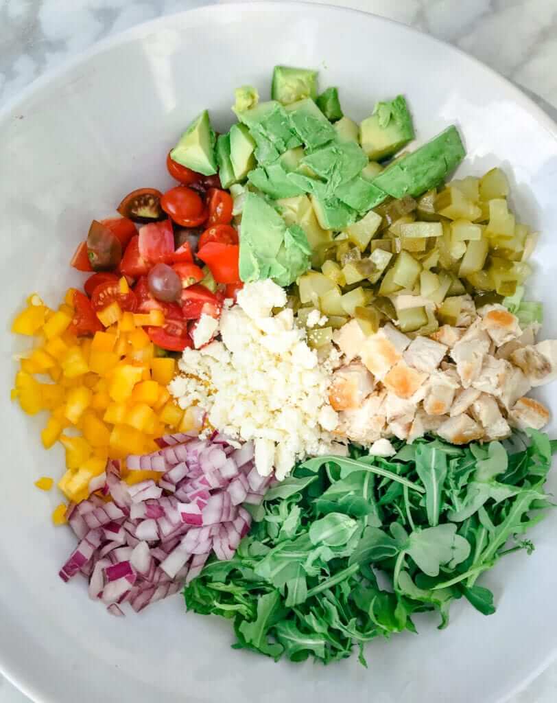 overhead shot of a healthy lunch salad packed with lean chicken,  arugula, peppers, cheese and avocado