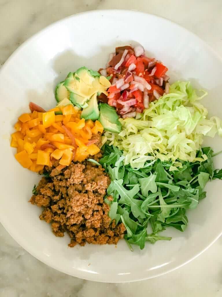 overhead shot of a healthy organic lunch salad with ground beef, arugula, bell pepper and tomatoes 