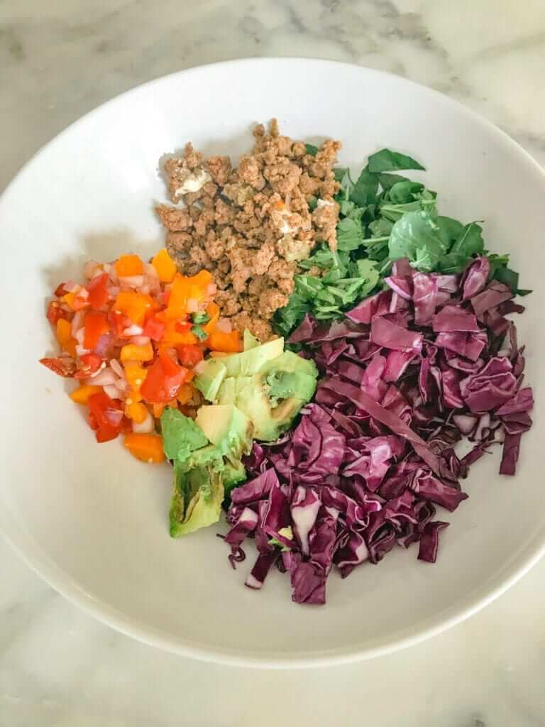 overhead shot of a meal prep lunch salad with leafy greens, red cabbage and ground beef 