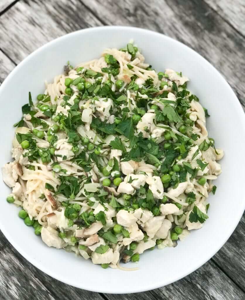overhead shot of a plate with creamy gluten-free chicken and mushroom pasta with peas and parsley