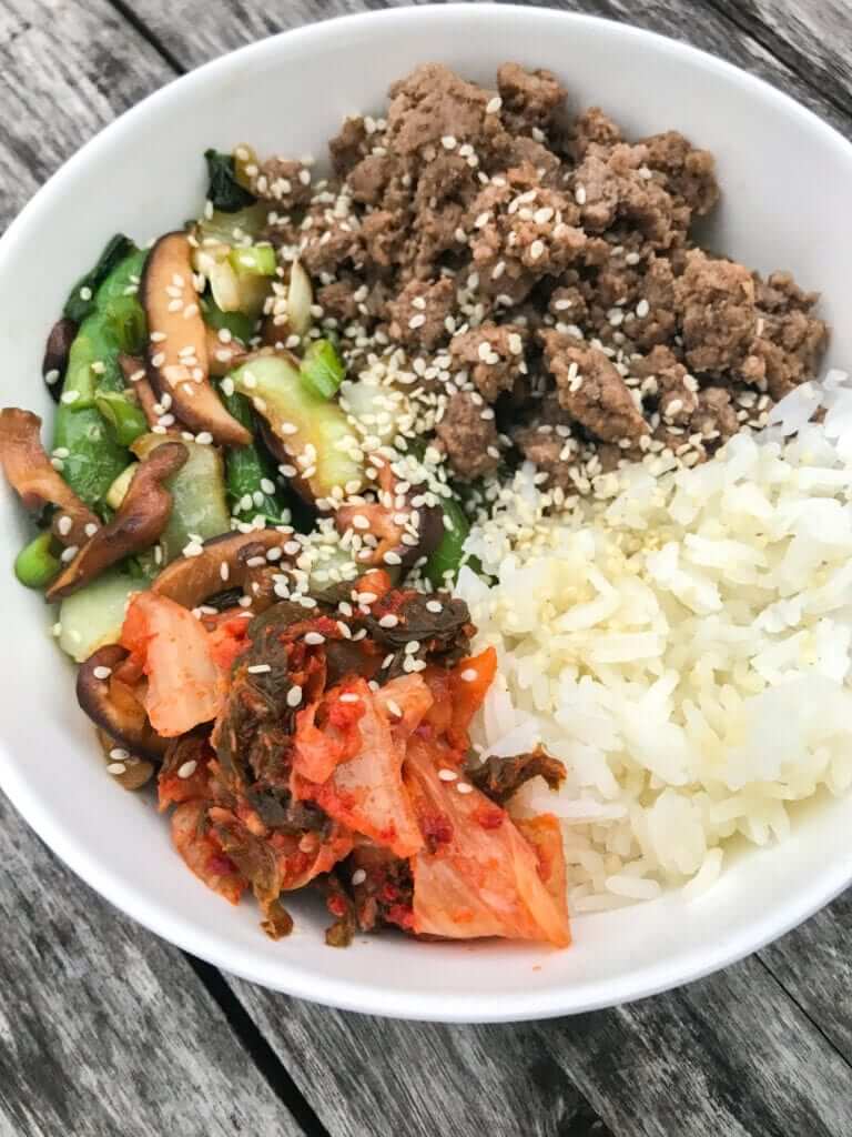 overhead shot of an Asian Bowl with ground Beef, rice and veggies sprinkled with sesame seeds 