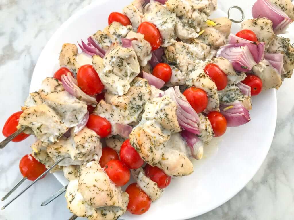 overhead shot of healthy Greek chicken kebabs on a white plate 