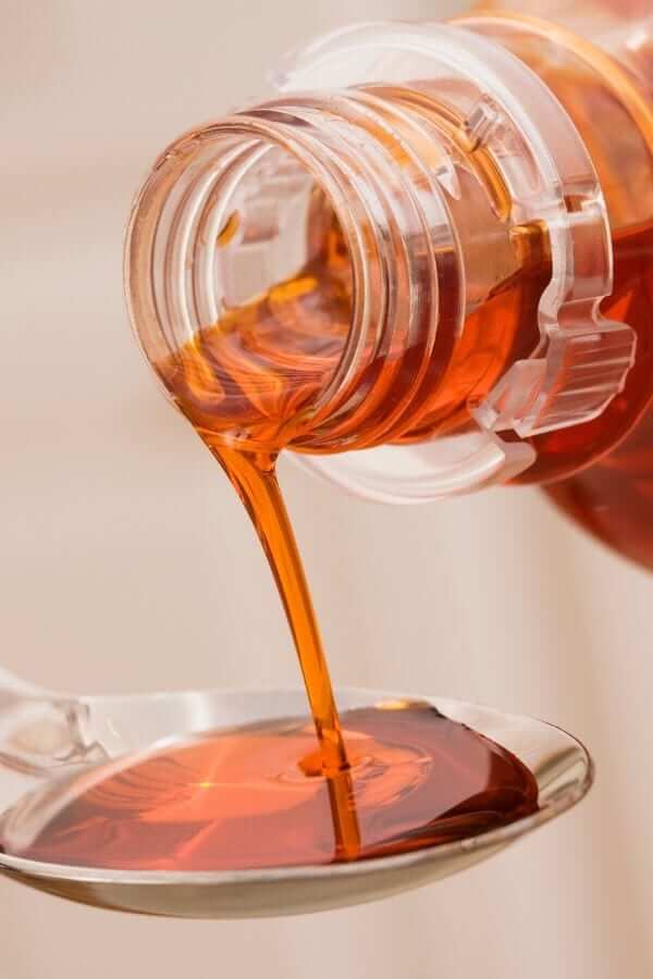 all natural immune boosting herbal cough syrup being poured onto a teaspoon